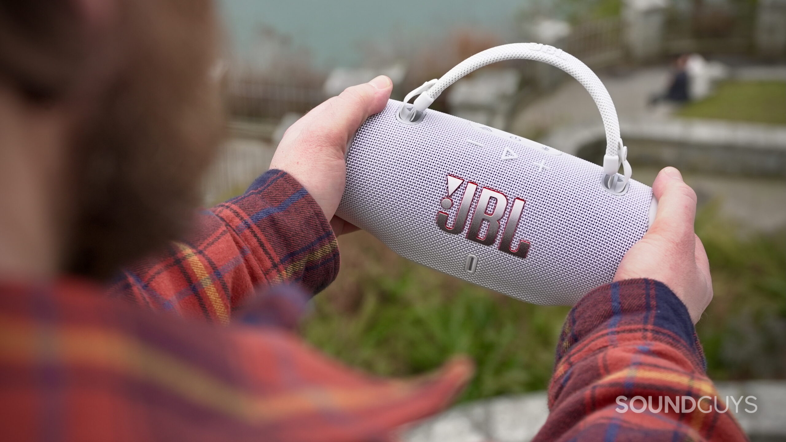 Charge 6 - 9 A man holding a JBL Charge 6 speaker but its sides.