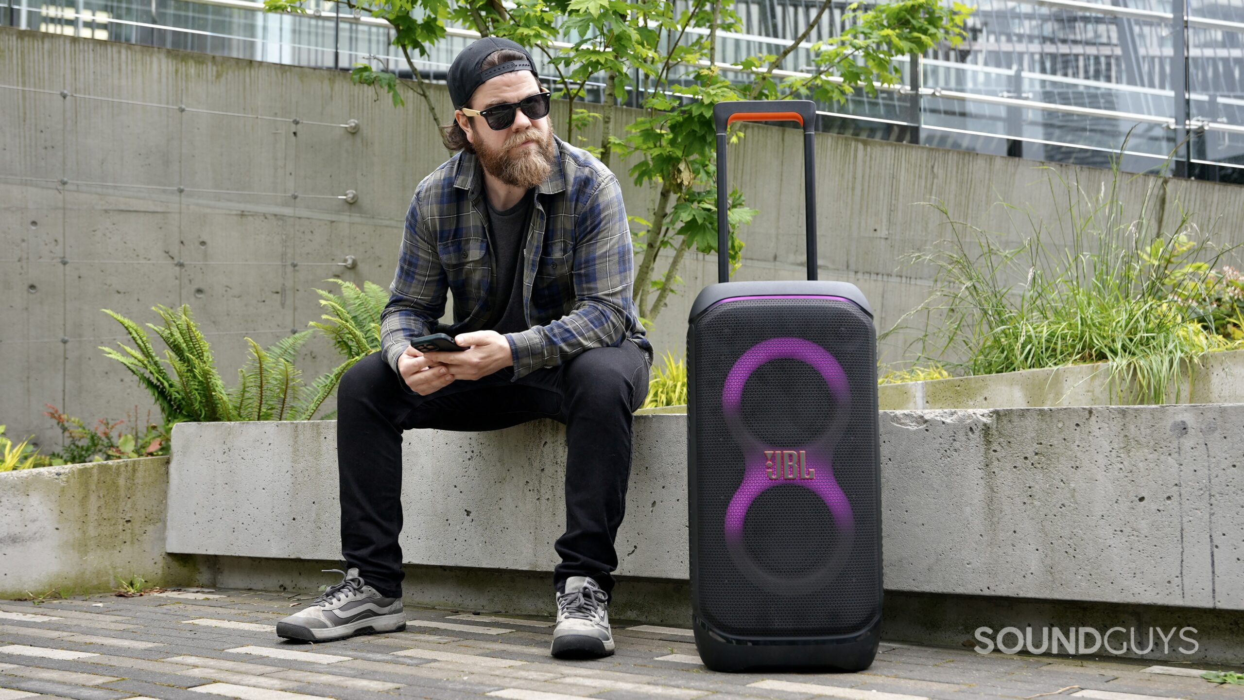A man sitting beside the JBL PartyBox 320 speaker