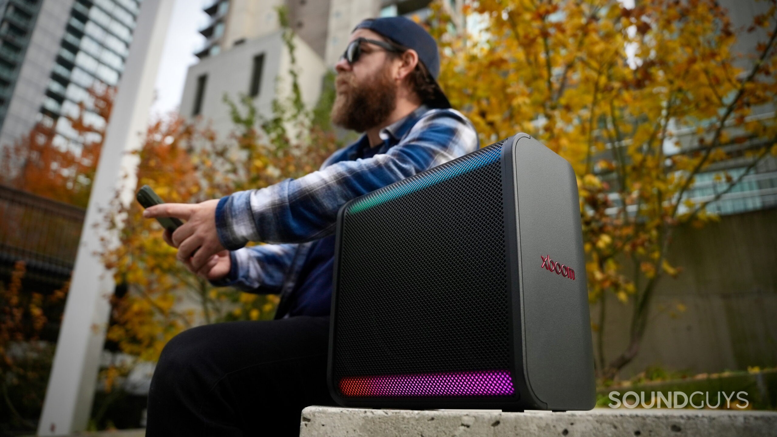LG xboom Stage 301 - 7 a man leaning on an LG xboom Stage 301 speaker in an outdoor setting.