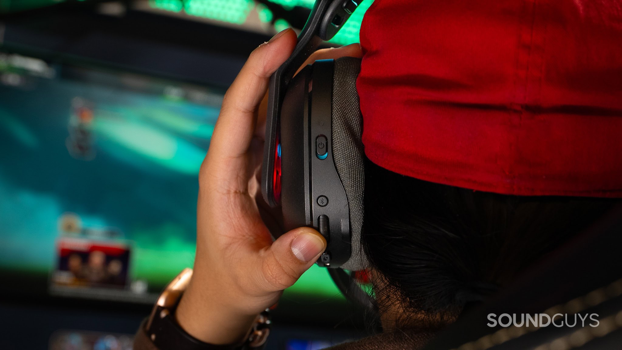 A close up of the left earcup of the Logitech A20 X as a person turns the volume roller.