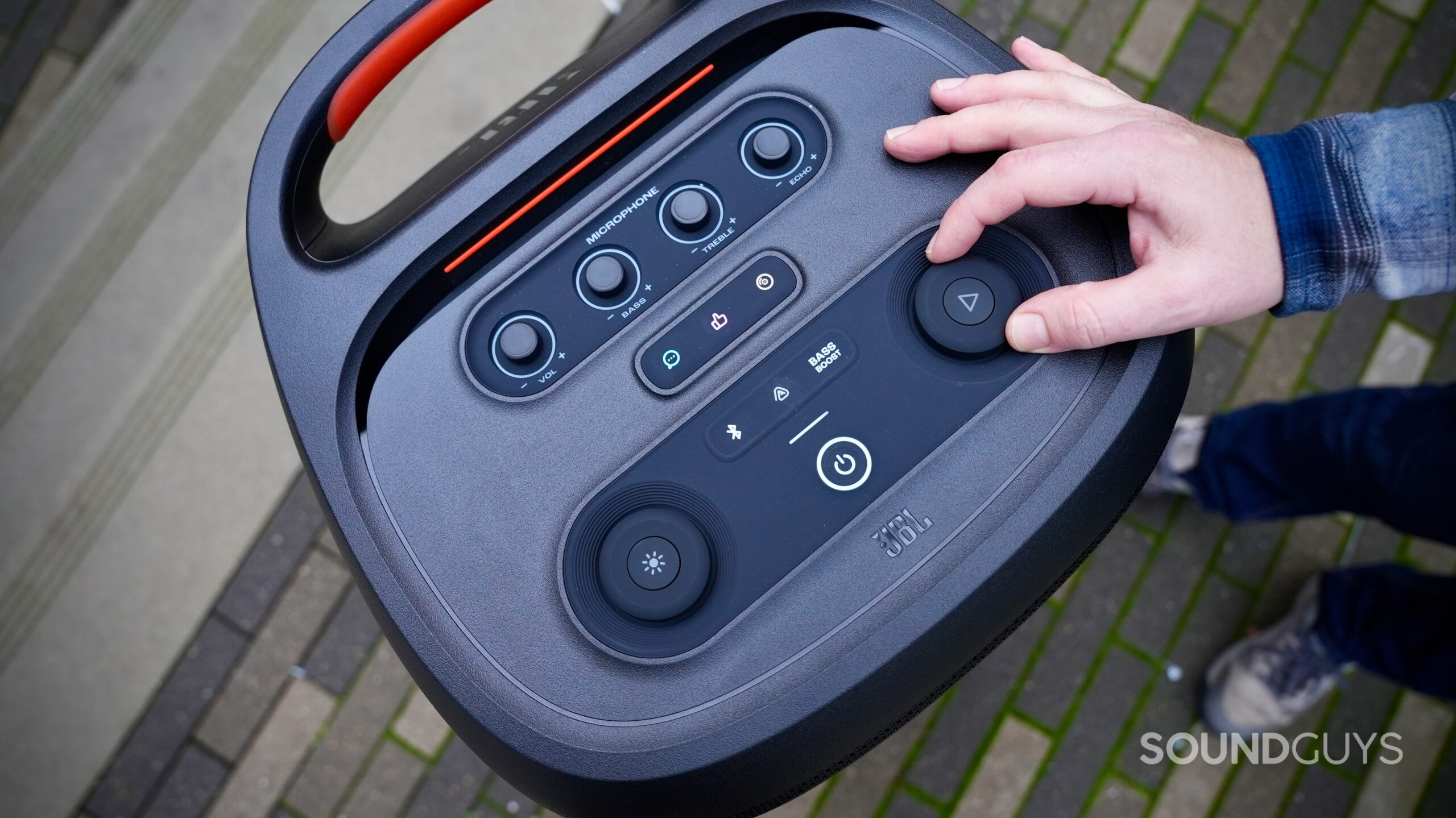 Photo of the JBL PartyBox 720 control panel with a hand adjusting the volume.