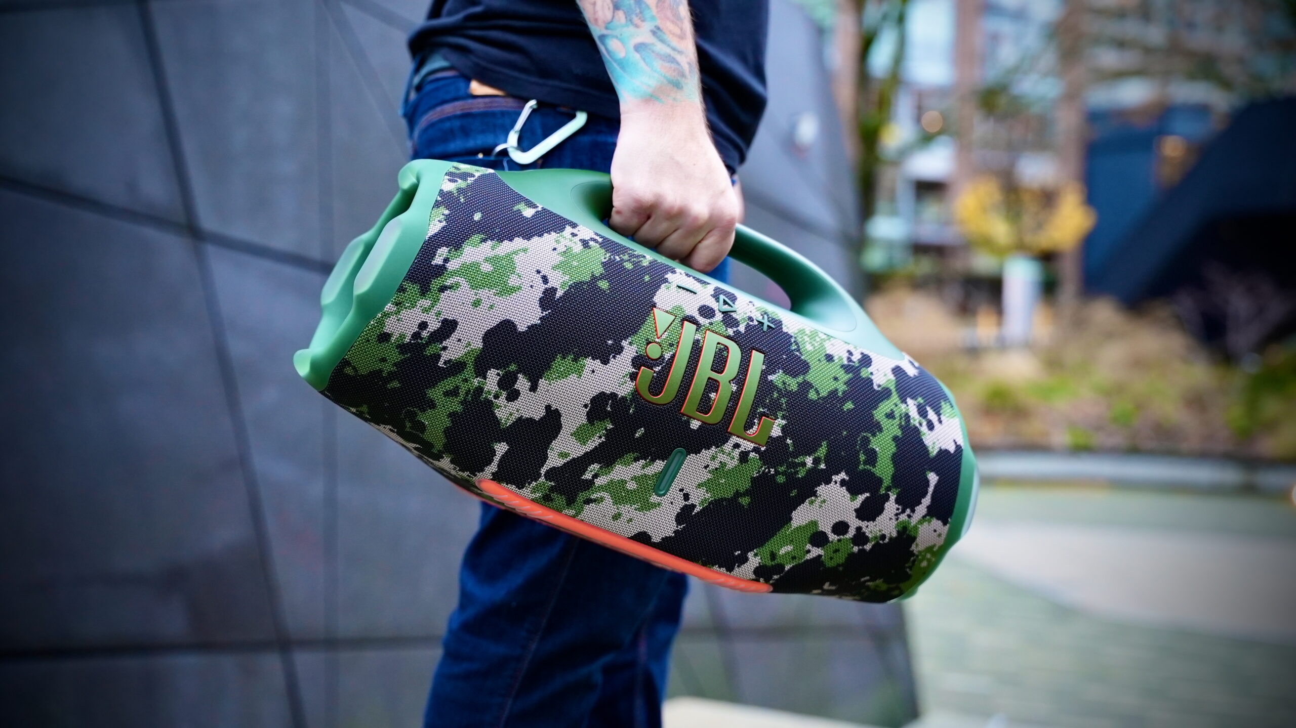 JBL Boombox (2.0) - 3 Side shot of a man carrying a camo JBL Boombox 4 by its handle.